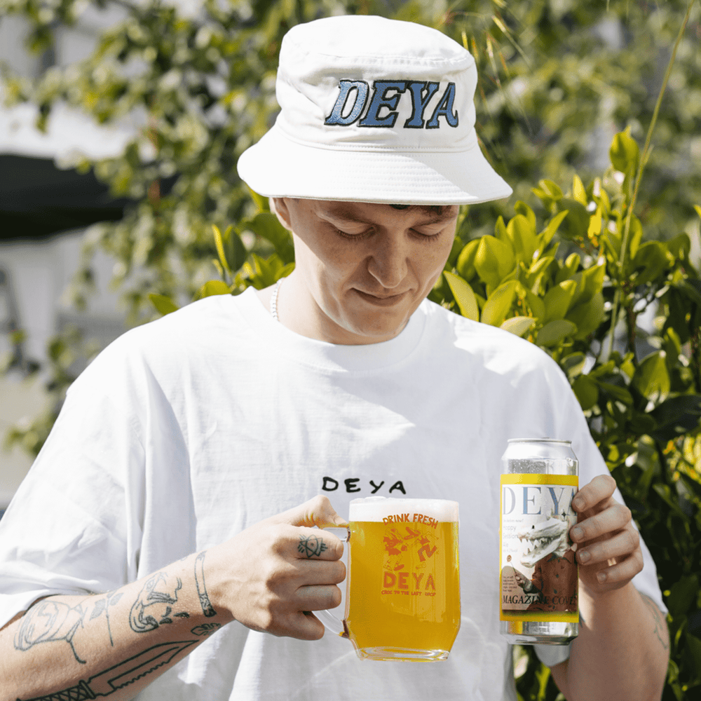 Jack wearing a "Big DEYA" bucket hat and holding a 500ml can of Magazine Cover Pale Ale and a DEYA Drink Fresh Tankard